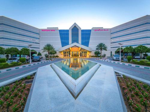 un grande edificio con una fontana di fronte di Mercure Grand Jebel Hafeet Hotel a Al Ain