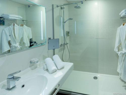 bagno bianco con lavandino e doccia di Mercure Cayenne Royal Amazonia a Cayenne