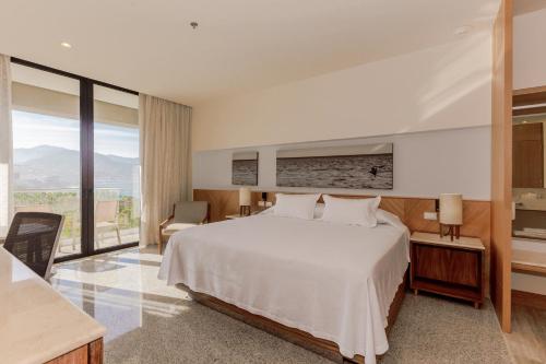 una camera con un letto bianco e una grande finestra di Hotel Mio Vallarta Unique & Different- Adults Only a Puerto Vallarta