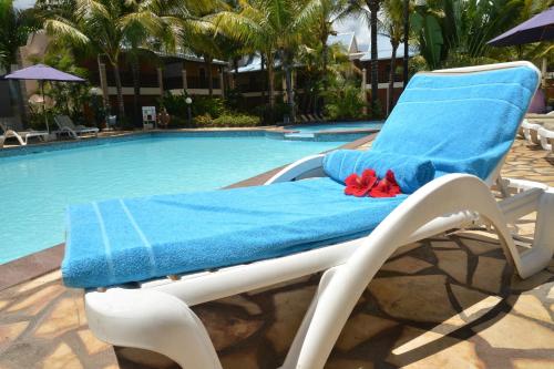 a lounge chair with a blue towel next to a swimming pool at Le Palmiste Resort & Spa in Trou aux Biches