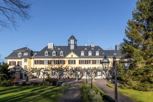 una vista esterna di un grande edificio giallo con alberi di Jagdschloss Hotel Niederwald a Rüdesheim am Rhein