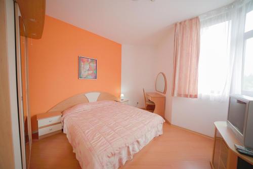 ein Schlafzimmer mit einem Bett mit einer orangefarbenen Wand in der Unterkunft Apartments Flora-Daisy in Borowez