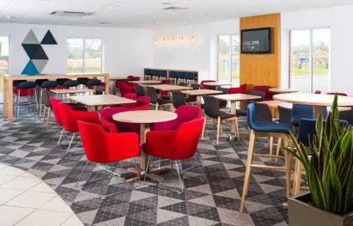 a restaurant with tables and chairs and a tv at Holiday Inn Express Southampton West, an IHG Hotel in Southampton