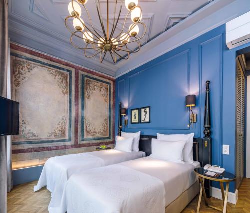 two beds in a room with blue walls and a chandelier at The Soul Istanbul Hotel in Istanbul