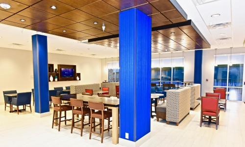 un ristorante con colonne blu, tavoli e sedie di Holiday Inn Express & Suites - Perryville I-55, an IHG Hotel a Perryville