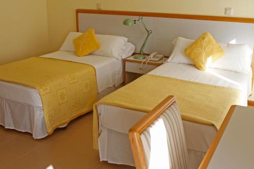 ein Hotelzimmer mit 2 Betten und gelben Kissen in der Unterkunft Hotel Playa de Merón in San Vicente de la Barquera