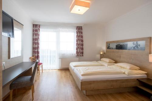 - une chambre avec un lit, un bureau et une télévision dans l'établissement Hotel-Restaurant Planaihof, à Schladming