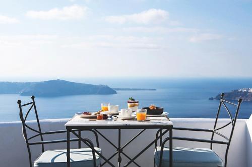 a table with food and drinks on a balcony overlooking the ocean at Remezzo Villas in Imerovigli