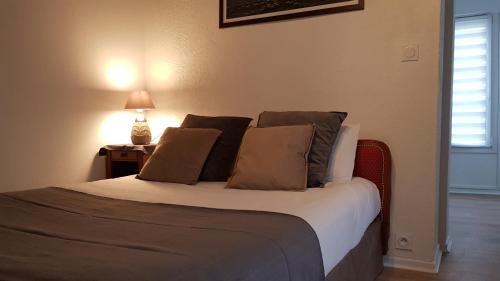 een slaapkamer met een bed met kussens en een lamp bij Hotel Saint Etienne in Caen