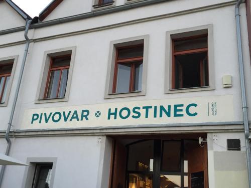 a white building with a sign that reads plyagon and hospice at Apartmány v pivovaru in Kašperské Hory