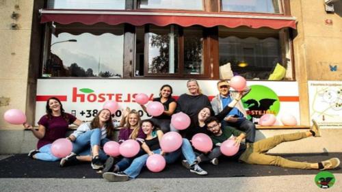 um grupo de pessoas segurando balões rosa na frente de um ônibus em Hostel 24 em Liubliana