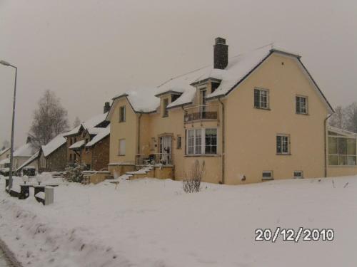 una casa coperta di neve in un cortile di B&B De Boerderij a Berdorf