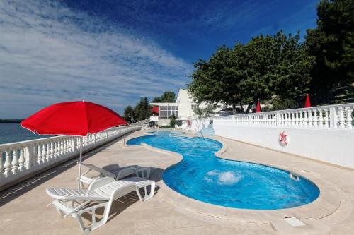 una sombrilla roja y sillas junto a la piscina en Hotel Val All Inclusive, en Trogir