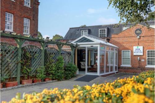 un invernadero frente a un edificio de ladrillo con flores en SK Baylis House Hotel, en Slough