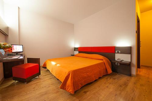 a bedroom with a bed and a desk with a computer at Hotel Plestina Ristorante Pizzeria in Foligno