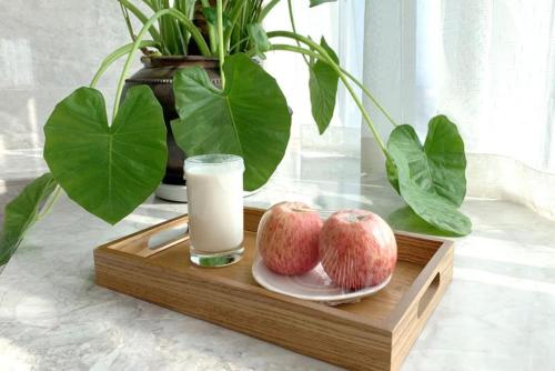 een houten dienblad met twee appels en een glas melk bij Bai Yun Qin She Boutique in Chongqing