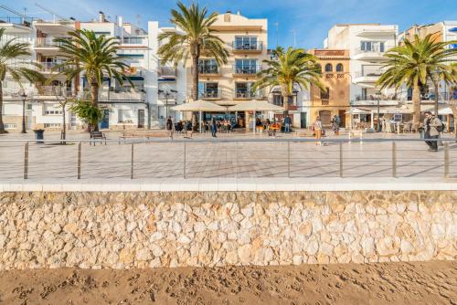 a view of a beach with palm trees and buildings at InSitges Sant Sebastia's Beach in Sitges