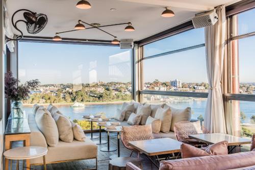 een kamer met grote ramen, banken en tafels bij Hotel Palisade in Sydney