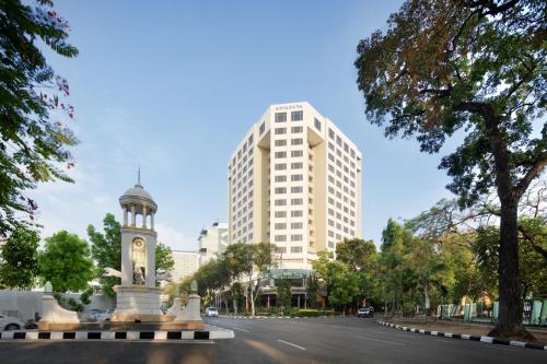 una calle de la ciudad con una torre del reloj y un edificio alto en Aryaduta Bandung, en Bandung