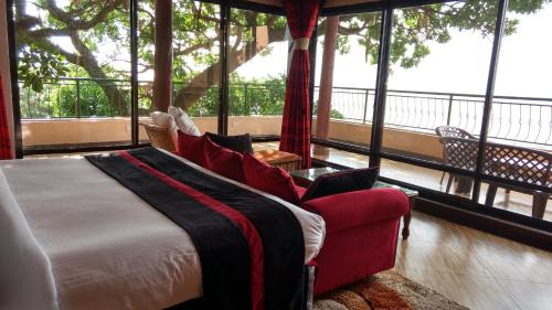 een slaapkamer met een bed, een bank en ramen bij Milimani Beach Resort in Kisumu