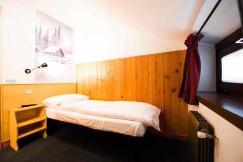 Habitación pequeña con cama y ventana en Hotel Teola, en Livigno