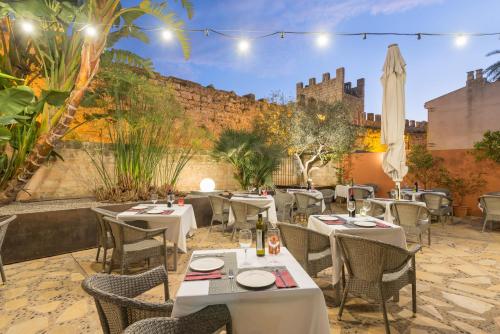 een restaurant met tafels en stoelen en een muur bij Alcudia Petit - Turismo de Interior in Alcudia