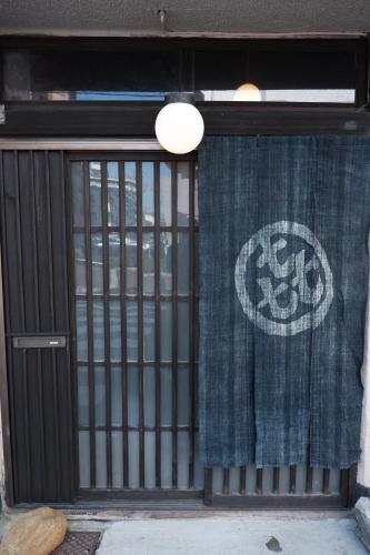 ein Tor mit einem Vorhang vor einem Gebäude in der Unterkunft 一棟貸ゲストハウス 傾㐂屋 Kabukiya in Hiroshima