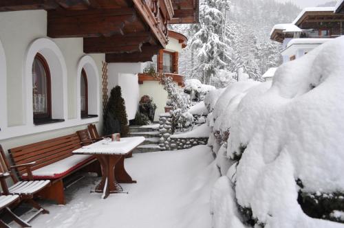 a snow covered yard with a table and benches at Gästehaus Sissy in Längenfeld