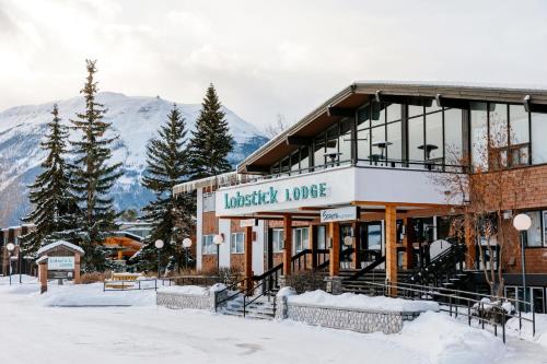 un edificio en la nieve con montañas en el fondo en Lobstick Lodge, en Jasper