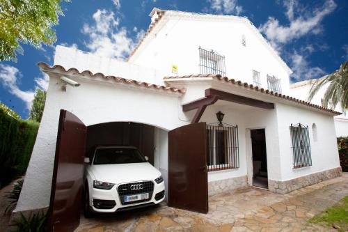 une voiture blanche garée devant une maison blanche dans l'établissement Sunway Torre La Veleta, à Sitges