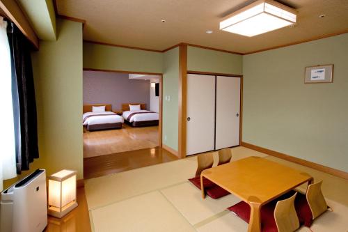 Zimmer mit 2 Betten, einem Tisch und einem Schlafzimmer in der Unterkunft Natural Hot Spring Yaoji Hakata Hotel in Fukuoka