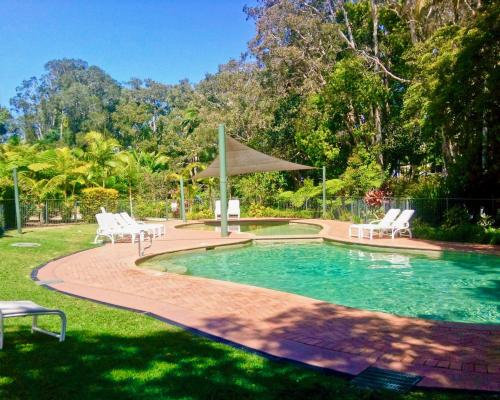 een zwembad met 2 stoelen en een parasol bij Beach Resort Apartment in Port Macquarie