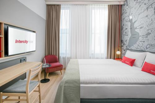 um quarto de hotel com uma cama, uma secretária e uma televisão em IntercityHotel Hamburg-Barmbek em Hamburgo