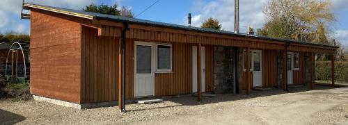 - un petit bâtiment en bois avec une porte blanche dans l'établissement Ivy Cottage-Serviced accommodation, à Dyce