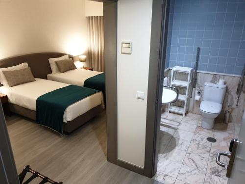 um quarto de hotel com duas camas e um WC em Apulia Praia Hotel em Esposende