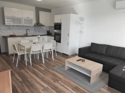 een woonkamer met een bank en een tafel en een keuken bij Hatvan Corner Apartments 2 in Debrecen