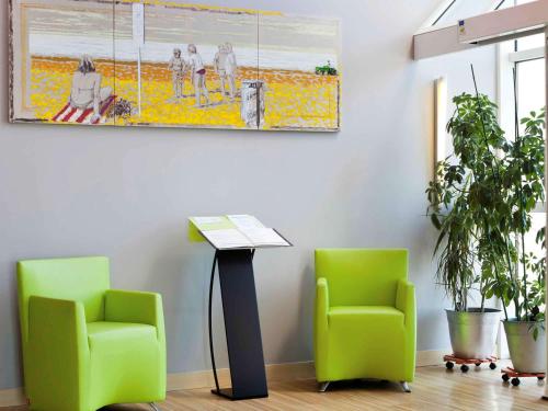 two green chairs and a table in a room at ibis Styles Ouistreham in Ouistreham