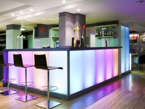 a bar with purple and pink bar stools at ibis Styles Ouistreham in Ouistreham