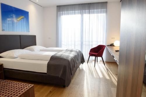 een slaapkamer met een bed en een bureau met een rode stoel bij Hotel Wallern Garni in Wallern an der Trattnach