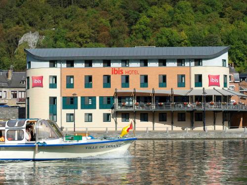 a boat in the water in front of a building at ibis Dinant Centre in Dinant