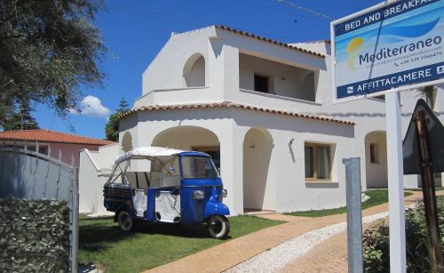 un pequeño vehículo azul estacionado frente a un edificio en Mediterraneo, en San Teodoro