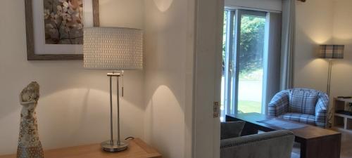 een woonkamer met een lamp, een stoel en een raam bij Loch Ness Abbey Cottages in Fort Augustus