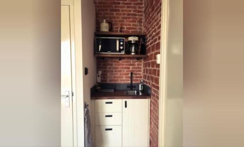 a kitchen with white cabinets and a brick wall at Queens Beachhouse in Zandvoort