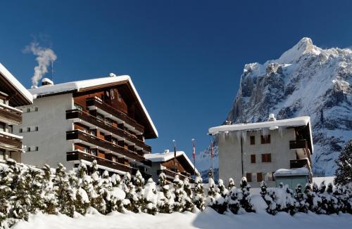 ein schneebedecktes Gebäude mit einem Berg im Hintergrund in der Unterkunft Hotel Residence in Grindelwald