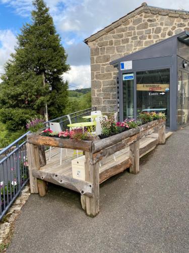 - un bâtiment avec une table en bois et des fleurs dans l'établissement Auberge de Thelis, à Thélis-la-Combe