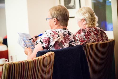 twee oudere mensen zitten in een stoel een boek te lezen bij Barrowfield Hotel in Newquay