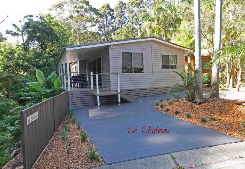 ein winziges Haus mit einer Veranda und einer Auffahrt in der Unterkunft The Palms At Avoca in Avoca Beach