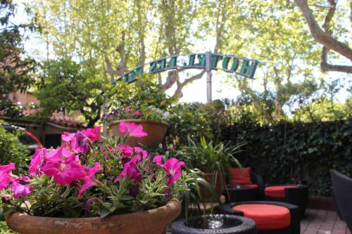 a garden with pink flowers and a street sign at Hôtel Les Palmiers in Saint-Tropez