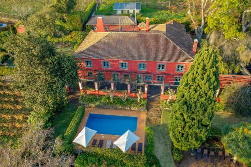 een luchtzicht op een groot rood huis met een zwembad bij Quinta das Vinhas in Calheta