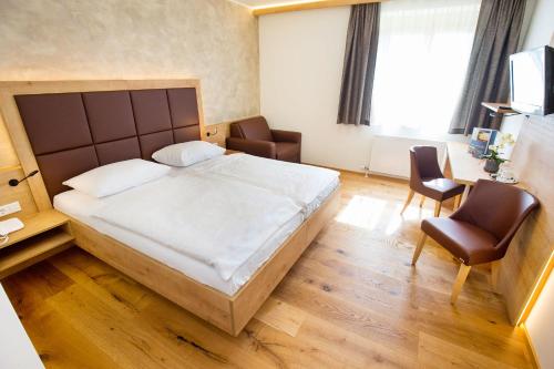 - une chambre avec un grand lit et deux chaises dans l'établissement Hotel Stich, à Manhartsbrunn